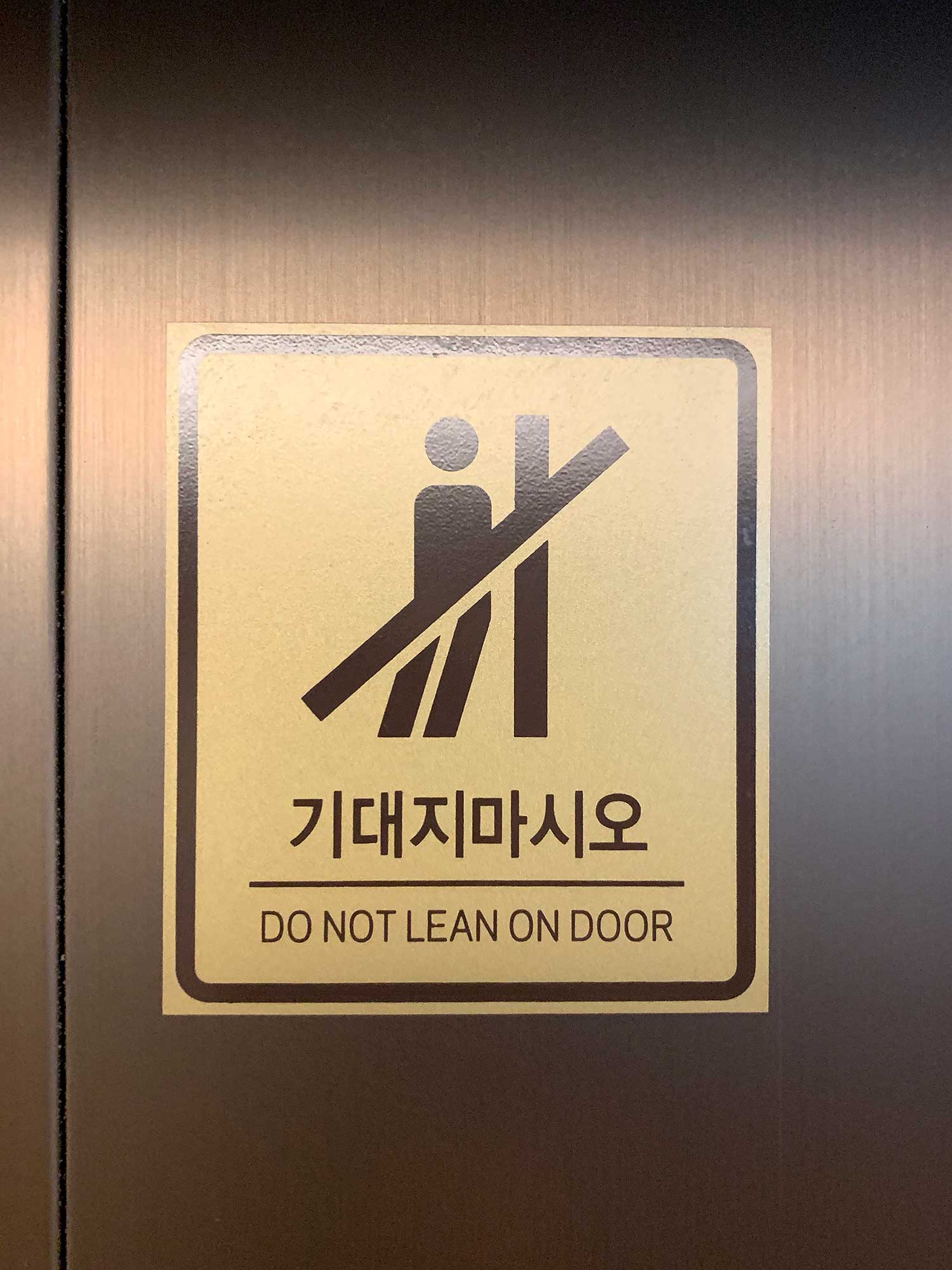 "Do not lean on elevator door" sign