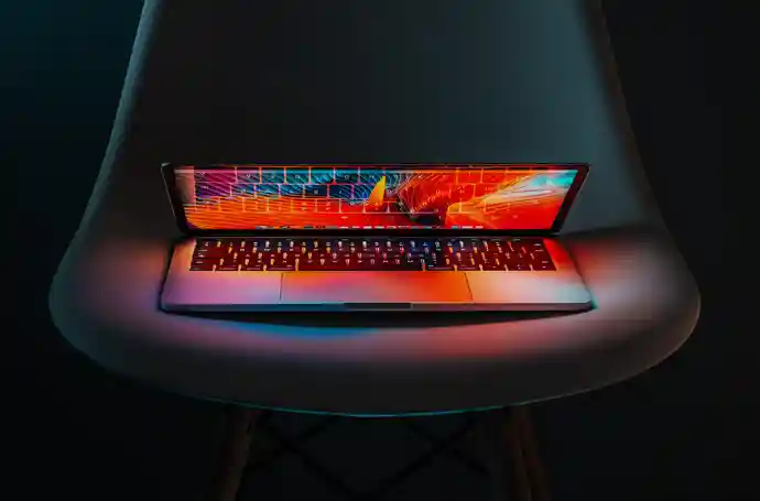 Lit up laptop sitting on plastic chair in the dark