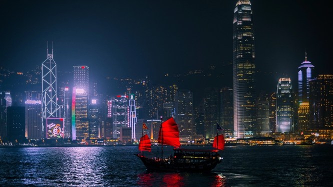 hong kong skyline at night with junk boat in foreground